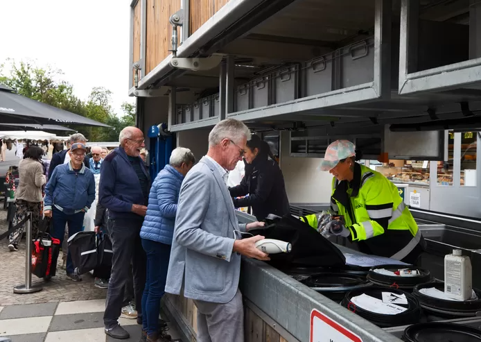 Oude mensen leveren oude accu in bij een verplaatsbare milieustraat in Gemert